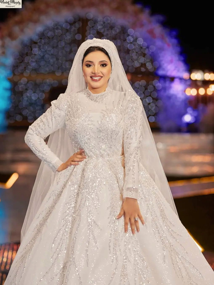 فستان زفاف طويل ابيض للمحجبات منفوش باكستنشن مضاف مطرز بالترتر والخرز اللامع و بطرحه من التل واكمام طويله - صور فساتين محجبات افراح